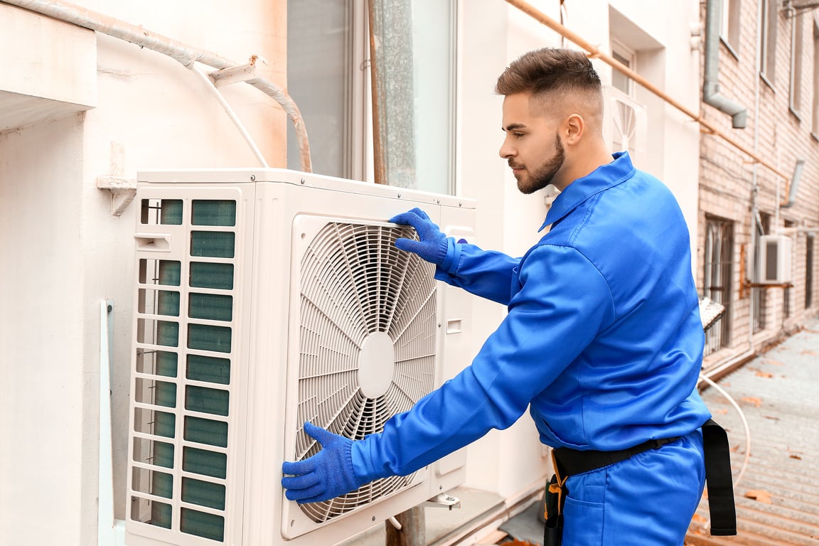 Male Technician Installing Outdoor Unit of Air Conditioner